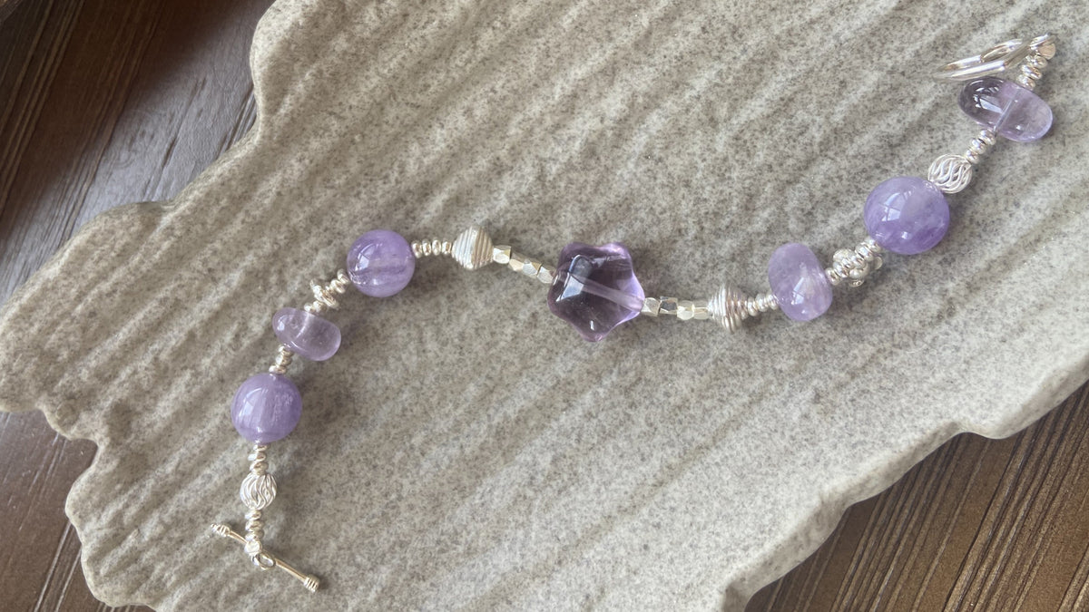 Violet Eclipse amethyst bracelet styled on a textured neutral surface