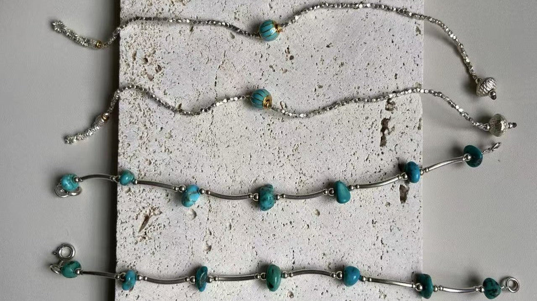 Turquoise and sterling silver jewelry arranged on a textured stone surface