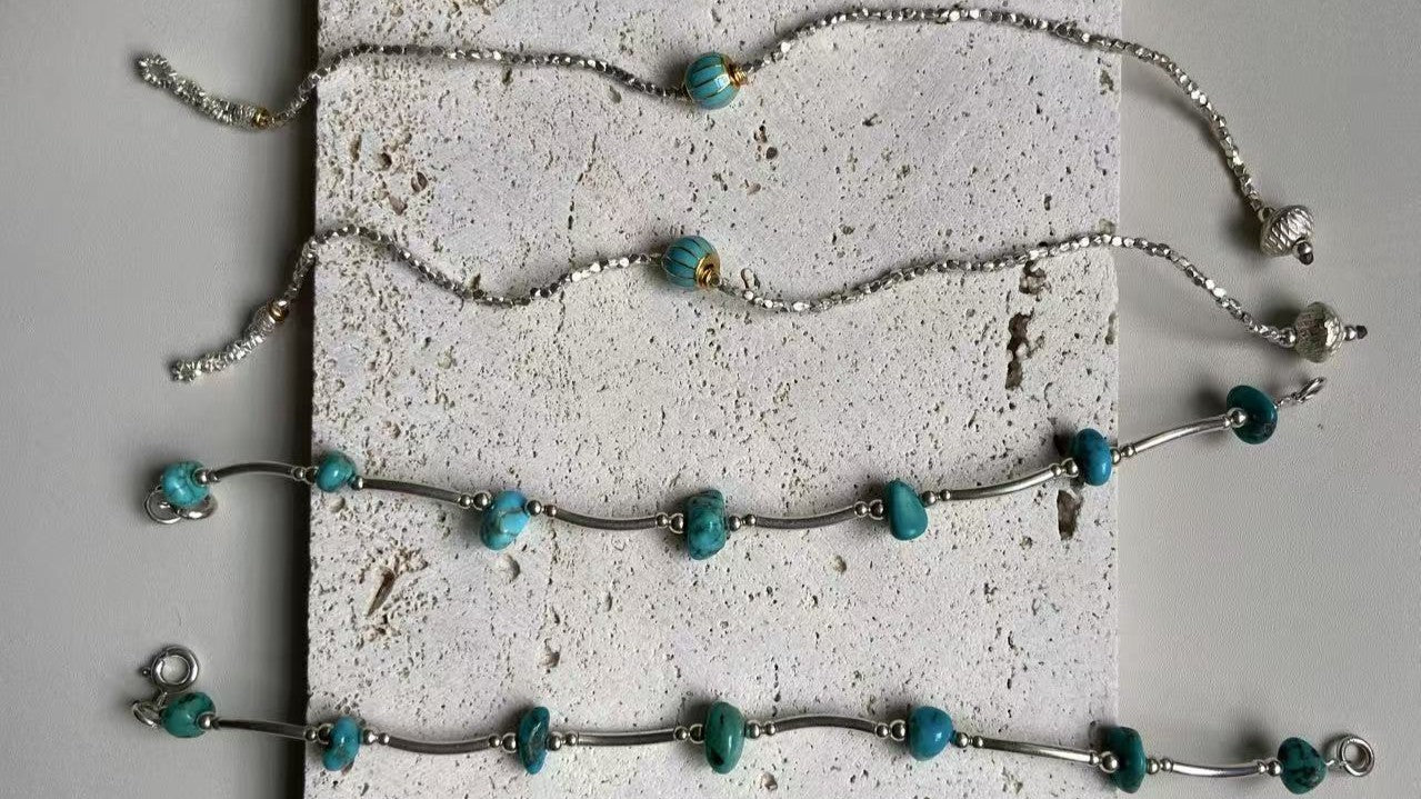 Turquoise and sterling silver jewelry arranged on a textured stone surface