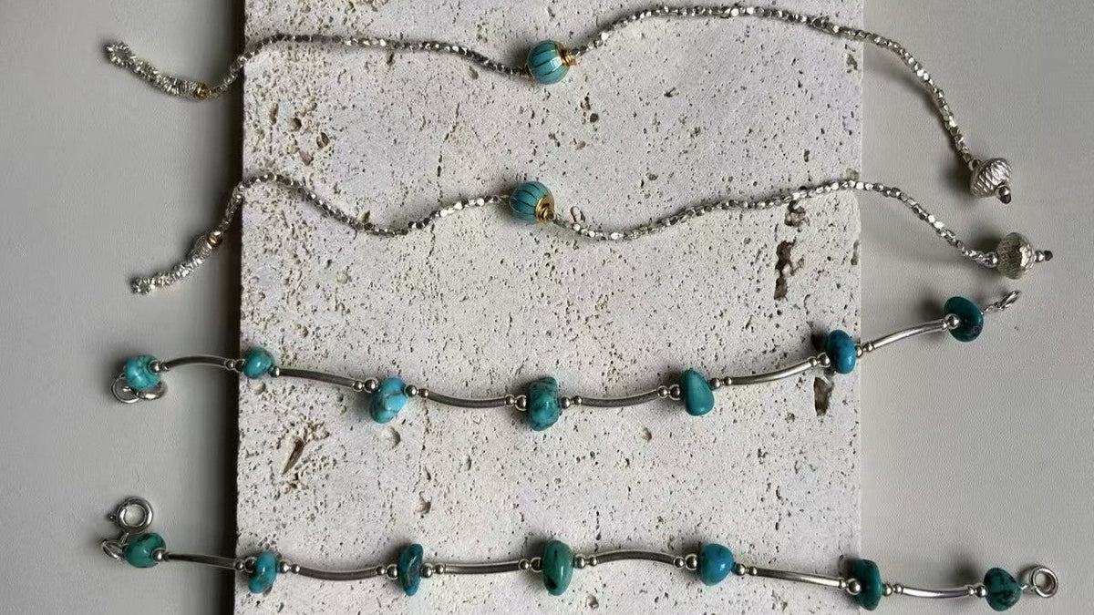 Turquoise and sterling silver jewelry arranged on a textured stone surface