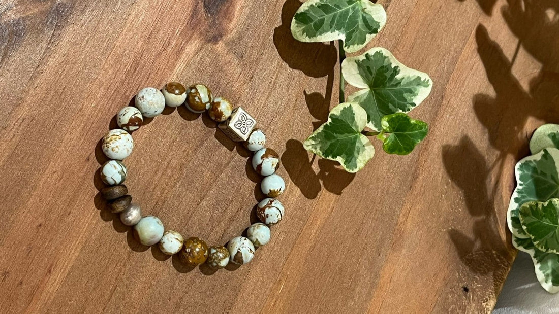 Whispering Canyon handmade picture jasper bracelet on a warm wooden surface beside green ivy