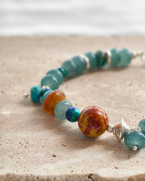 Close-up of teal stone beads with warm orange accent beads