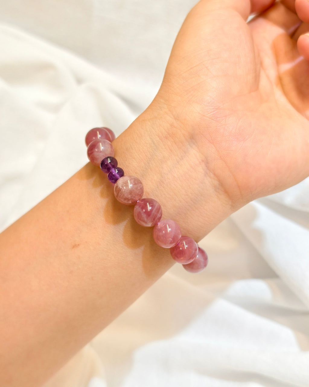 Handmade pink natural stone bracelet worn on the wrist in natural light