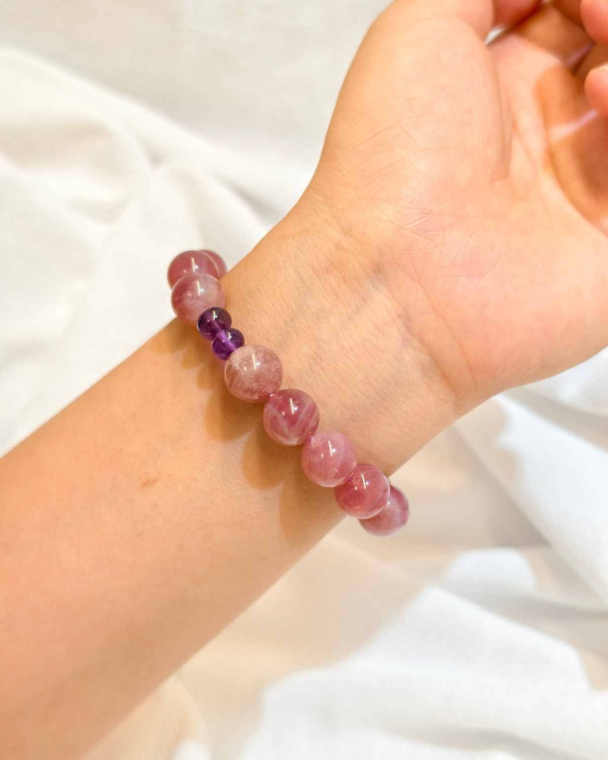 Handmade pink natural stone bracelet worn on the wrist in natural light