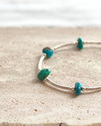 Close-up of turquoise tone stone beads with silver accents on a handmade bracelet