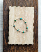 Turquoise tone natural stone bracelet styled on handmade paper and wooden background