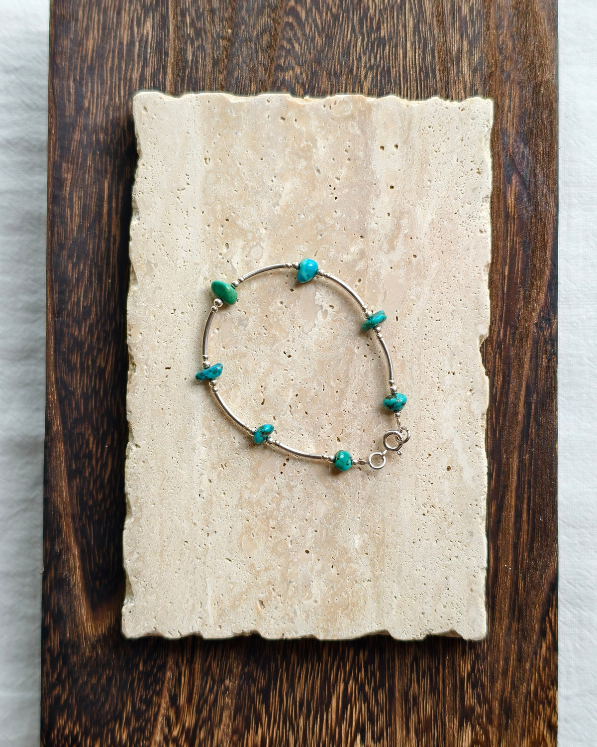 Turquoise tone natural stone bracelet styled on handmade paper and wooden background