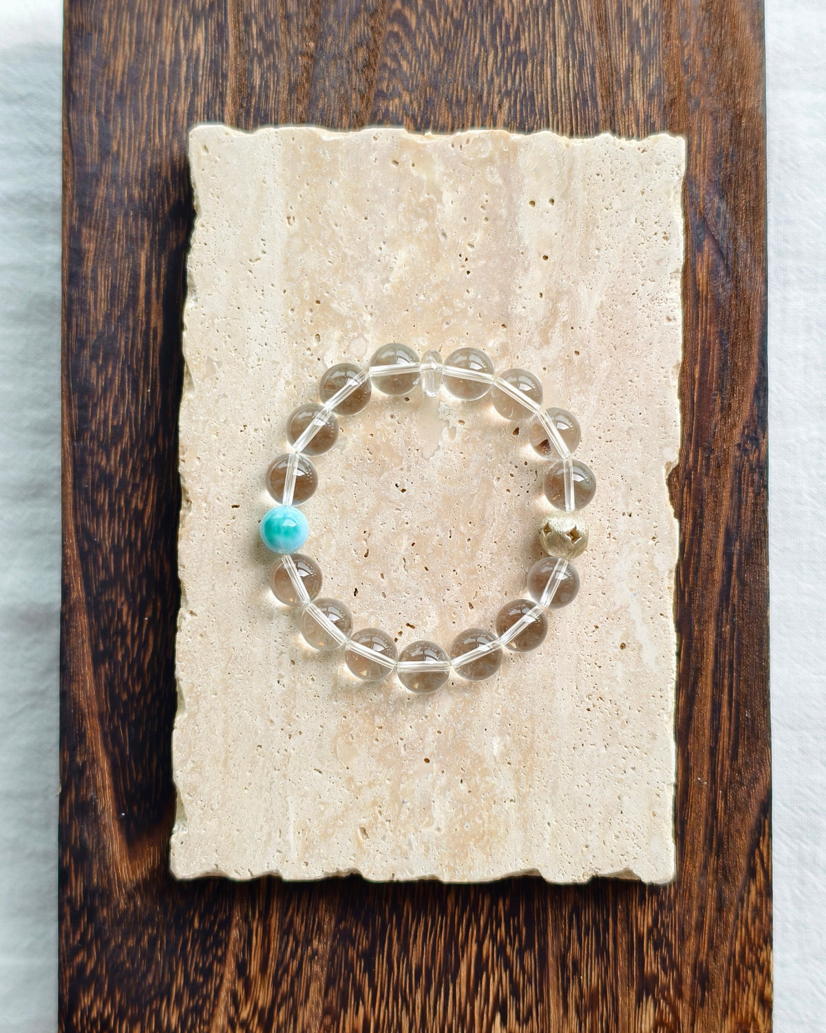 Minimal clear crystal bracelet displayed on handmade paper background