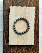 Dark natural stone bracelet styled on handmade paper and wooden background