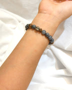 Dark natural stone bracelet with earthy tone beads worn on the wrist