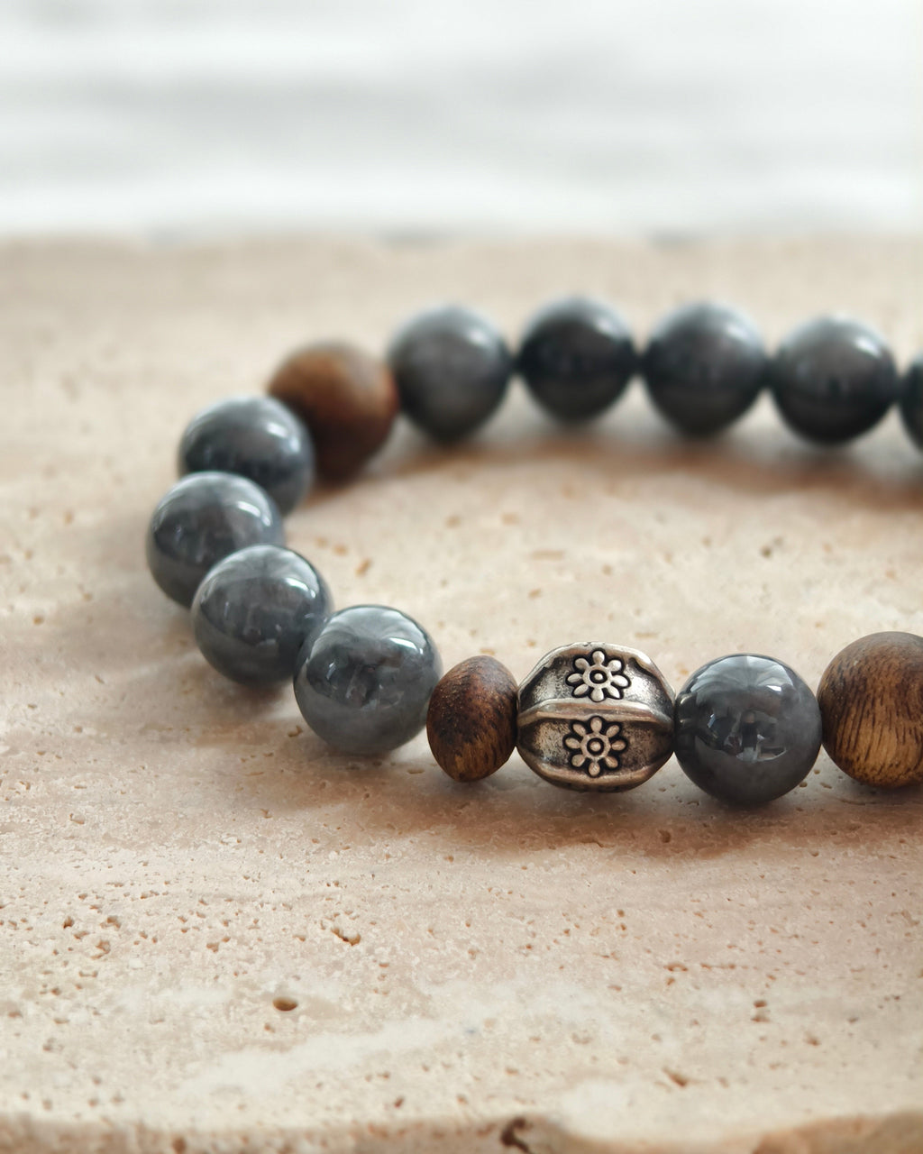Close-up of dark natural stone beads with brown accents and decorative metal spacer