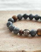 Close-up of dark natural stone beads with brown accents and decorative metal spacer