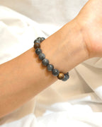 Handmade dark gemstone style bracelet worn on the wrist in soft natural light