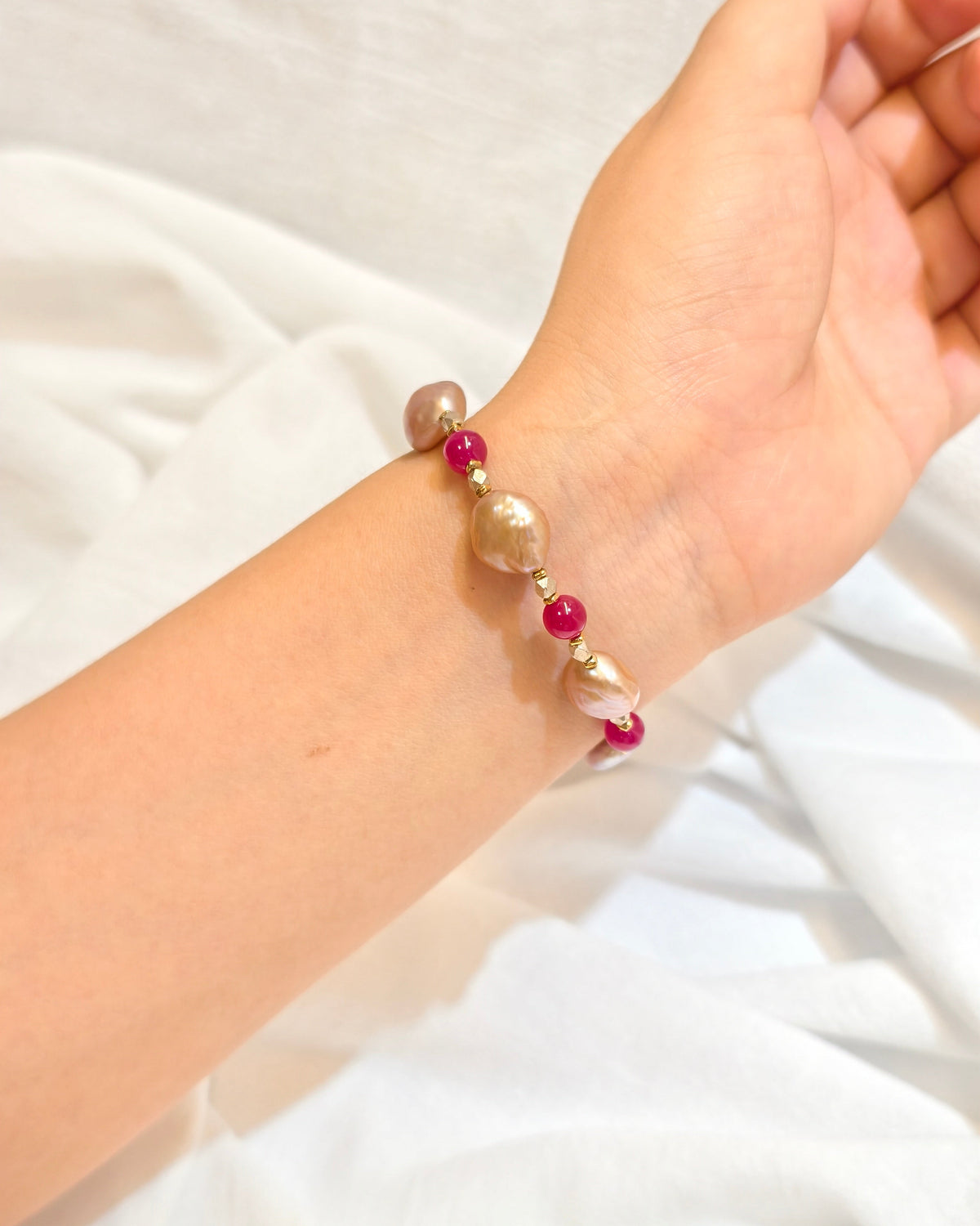 Elegant handmade pearl bracelet with pink accents worn on wrist