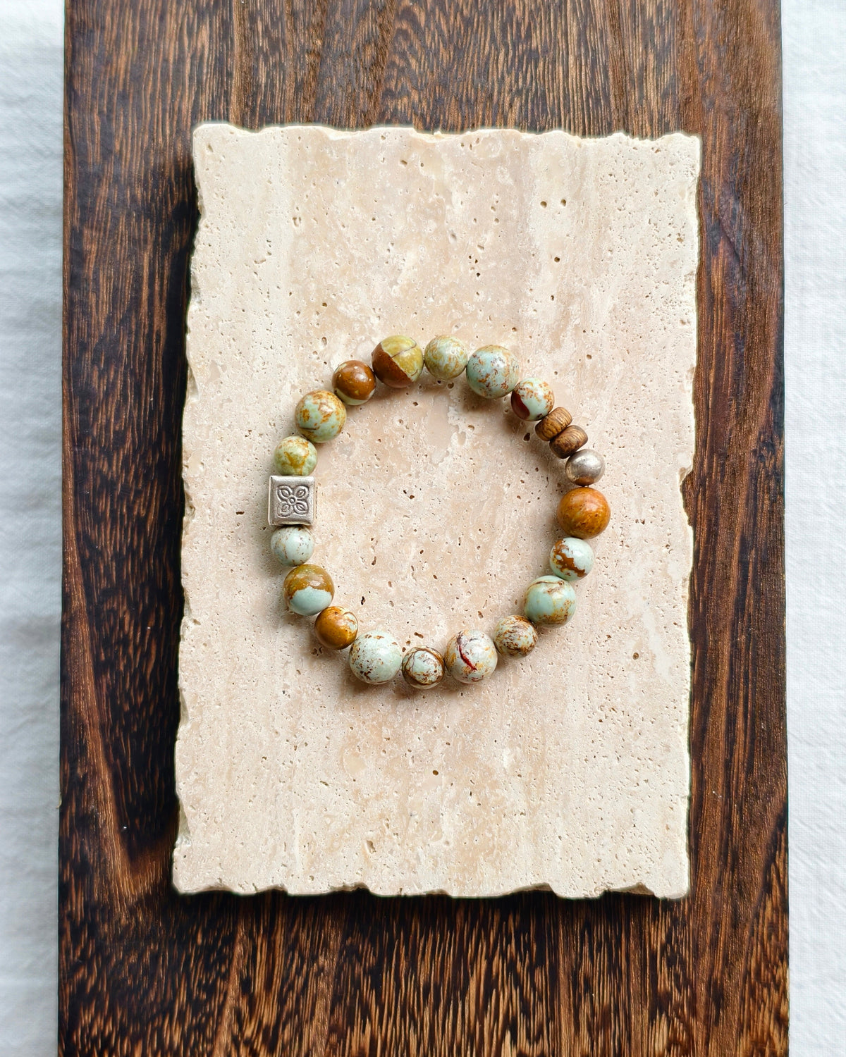 Whispering Canyon bracelet styled on handmade paper and a wooden surface