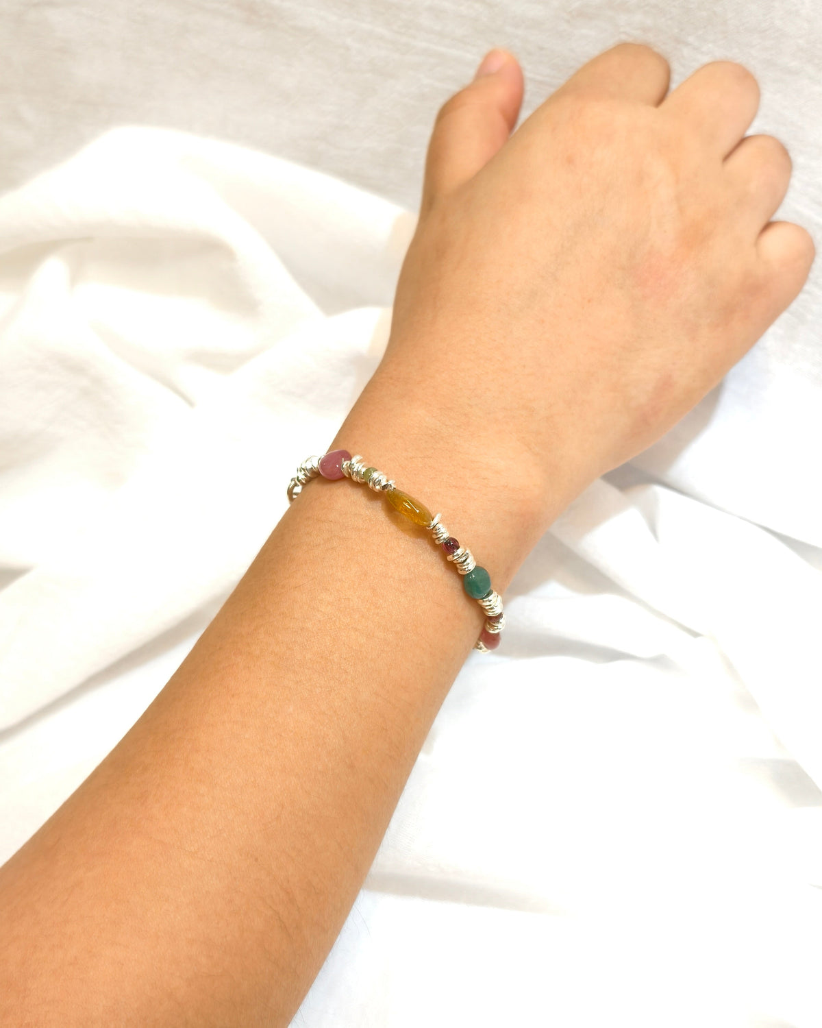 Colorful handmade gemstone bracelet with silver details worn on wrist